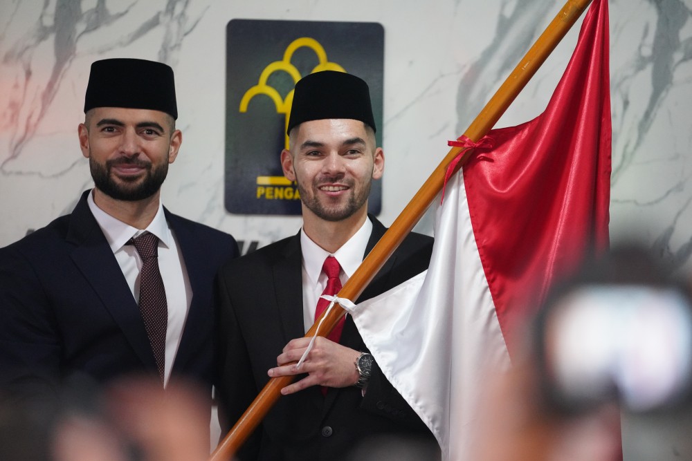 Pesepak bola Jordi Amat (kiri) dan Sandy Walsh memegang bendera merah putih seusai mengucapkan Sumpah dan Janji Setia Pewarganegaraan.  MI/BRIYANBODO HENDRO